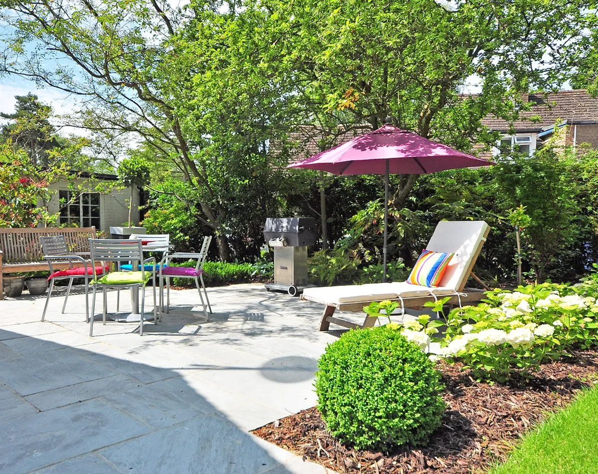 Terrasse ensoleillée avec une bordure de fleurs et de plantes colorées